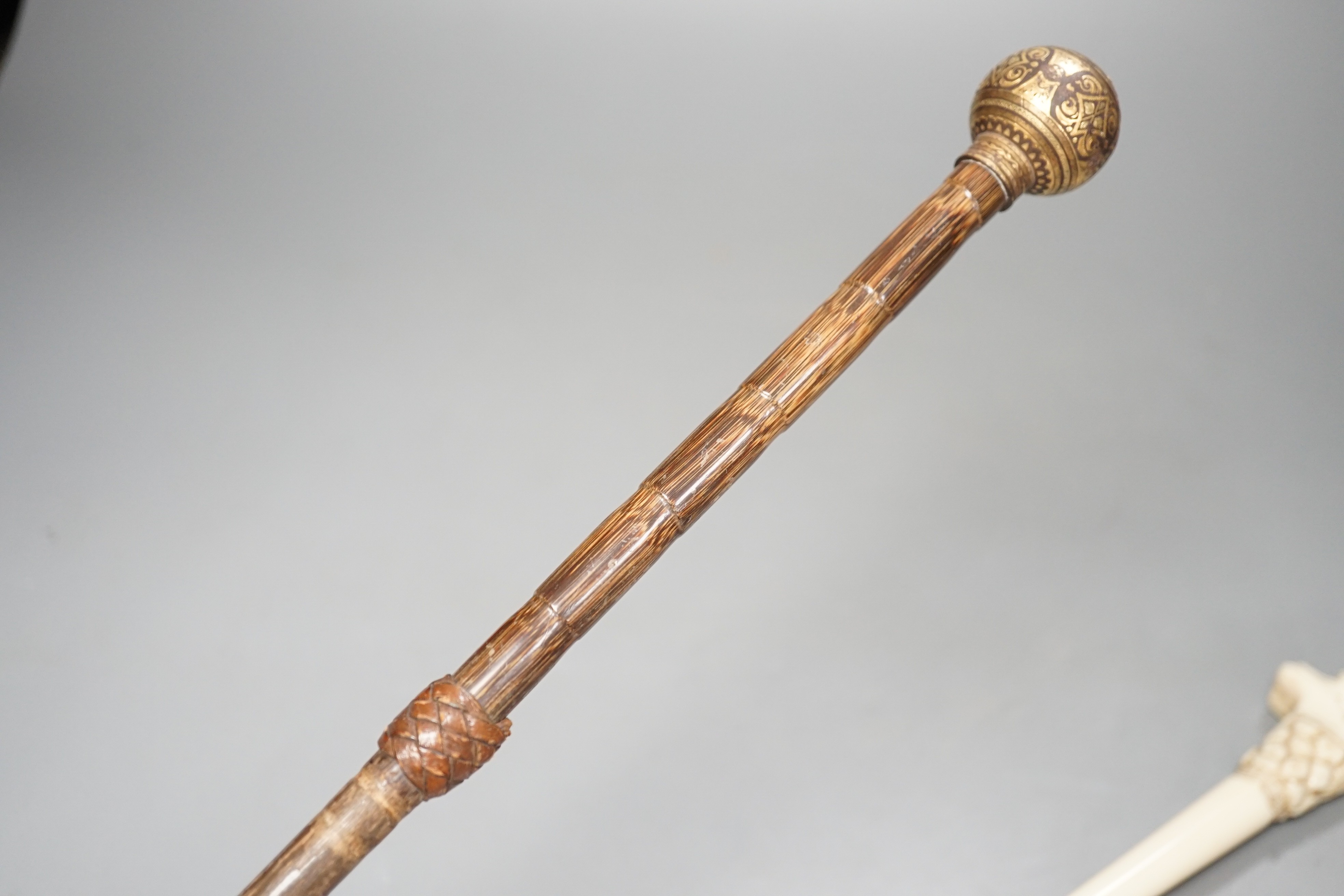 An early 20th century ivory ‘sphinx’ parasol handle, 84cm, together with another gold and iron damascened parasol handle, 62cm